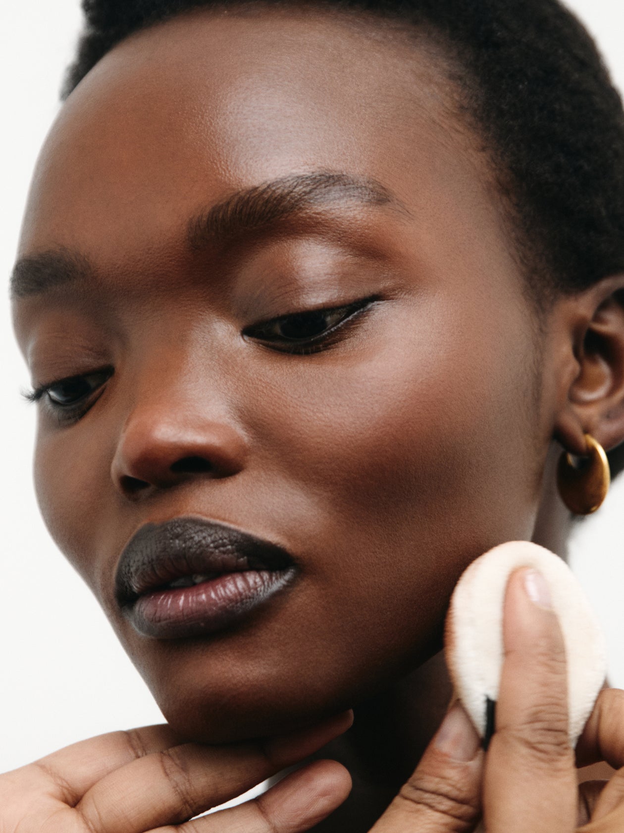 Close-up of a person applying makeup with a sponge applicator.