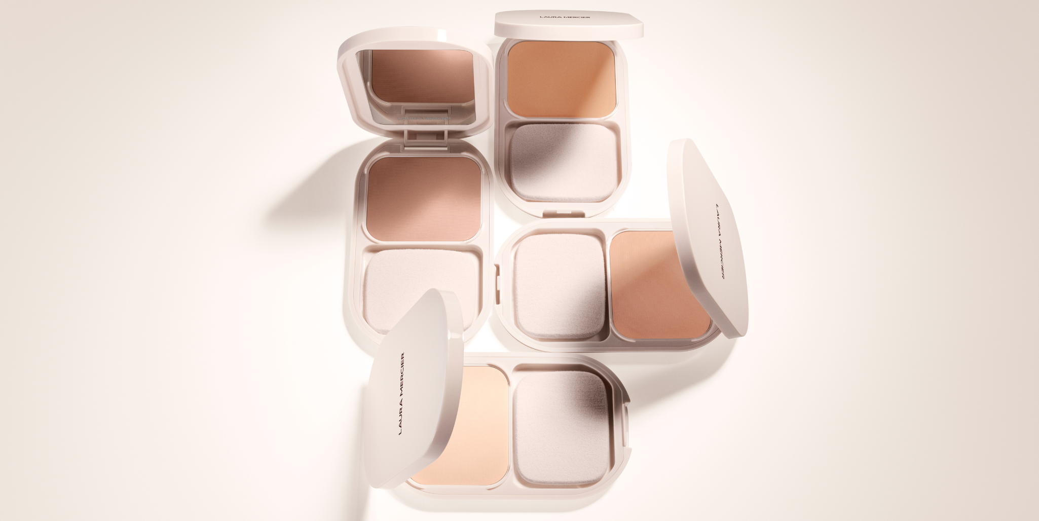 Laura Mercier's Real Flawless Feather Matte Powder Foundation shades on a light beige background