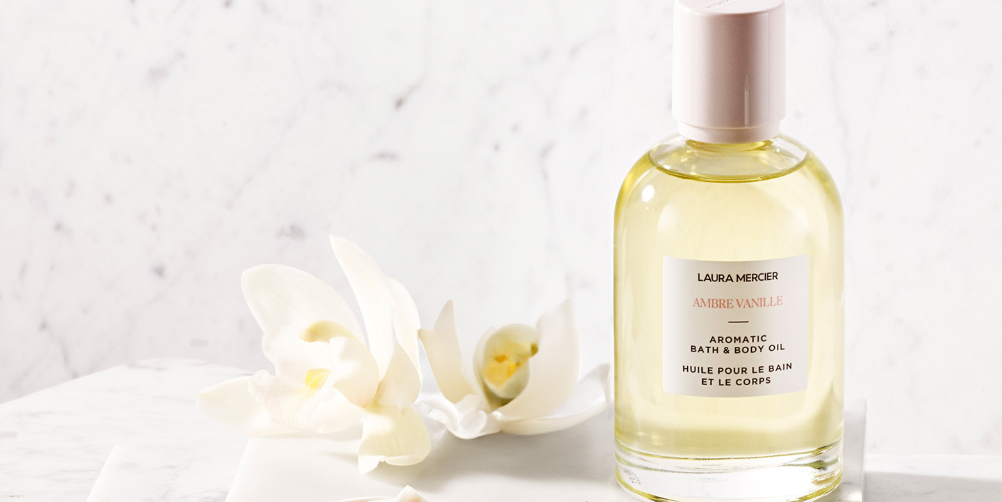 Laura Mercier Ambre Vanille Perfum next to white lily flower