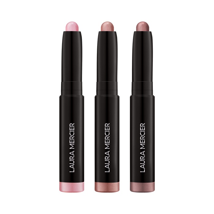 Three Laura Mercier eye shadow sticks  on a transparent background